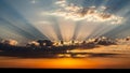 Dramatic sunset with sun rays bursting through dark clouds over orange sky Royalty Free Stock Photo