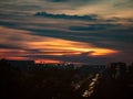 Dramatic sunset view over a modern city with illuminated building lights and orange sky Royalty Free Stock Photo