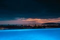 Dramatic tropical Sunset in Thailand - view over roof top swimming pool in luxury hotel. Blue highlighted pool Royalty Free Stock Photo