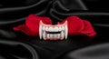 Dramatic vampire teeth on black silk with red rose petals create a spooky and mysterious mood Royalty Free Stock Photo