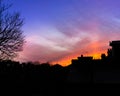 Vibrant, fire-like orange sky above silhouette of urban houses