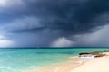 Dramatic view of dark grey storm clouds against the turquoise blue water of the Caribbean sea and a white sand beach Royalty Free Stock Photo