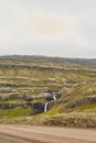 Dramatic view of small river with waterfall on mountains on a foggy autumn day with cloudy gray sky. Wild nature