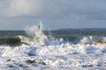 A dramatic view of a very choppy sea with huge crashing waves on groynes breakwater during a major storm under a grey sky