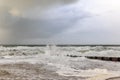 A dramatic view of a very choppy sea with huge crashing waves on groynes breakwater during a major storm under a grey sky