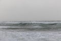 A dramatic view of a very choppy sea with huge crashing waves during a major storm under a grey sky