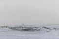 A dramatic view of a very choppy sea with huge crashing waves during a major storm under a grey sky