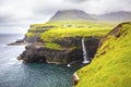 Dramatic waterfall on Faroe Islands and the village Gasadalur