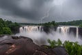 dramatic waterfall scene with stormy skies and lightning bolts during thunderstorm