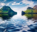 Drangarnir cliffs reflected in the calm waters of Atlantic ocean.