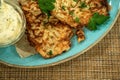 Draniki - potato pancakes on the blue plate served with sour cream and greens.