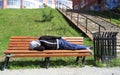 Drank man rests on a bench in park