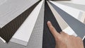 drapery catalog samples palette. architect's hand choosing samples of roller blind fabrics in different textures and colors.