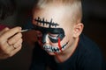 Draw on the boy`s face. Emotional portrait with a scary zombie on his face, horror concept - screaming the walking dead zombie Royalty Free Stock Photo