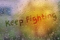 Draw text Keep Fighting on natural water drops glass window back Royalty Free Stock Photo