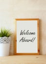 Drawing board with the phrase welcome aboard handwritten over wooden table.