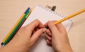 Drawing brushes, pencil, pens, paper clip, white blank notebook and both female hands open the pen on a wooden background Royalty Free Stock Photo