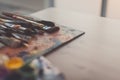 Drawing classes tools in art studio. Angle view photo of paintbrushes lying on palettewith oil paints brushstrokes Royalty Free Stock Photo
