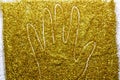 Drawing a hand with fingers on the golden sand glitter. Ahand against a gold texture on the glitter background. A Shiny gold Royalty Free Stock Photo