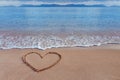 A drawing of a heart as a love symbol on a yellow sand at sea Royalty Free Stock Photo