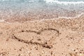 Drawing of a heart on the sand on the beach and wave with foam. Sea travel and holiday. Royalty Free Stock Photo