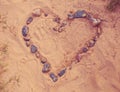 Drawing Heart of stones laid on warm sand. Toned, soft focused Royalty Free Stock Photo