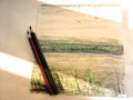 Sepia drawing with a pastel and pencil sketch with a view of the sea, two pencils and bright streaks of sunlight