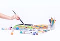 Drawing a picture, female hand close-up, stationery, paint brushes, on a white background