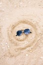 Drawing on sand, drawn smile in the form of a spiral, in sunglasses