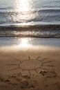 Drawing sun on a sandy beach near to sea. The symbol of resting in sunny day on vacation rest Royalty Free Stock Photo