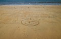 Smiley face with sea behind, drawn in the golden sand of Little Royalty Free Stock Photo