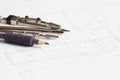 Drawing tools, a pencil and two compasses, against the background of an architectural plan for the construction of a house. Close- Royalty Free Stock Photo