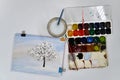 Drawing of a tree covered with fluffy snow and open watercolor paints on white background