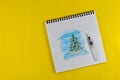 Drawing with watercolors, young green Christmas tree covered with fluffy snow, album on yellow paper background Royalty Free Stock Photo