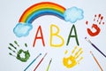 Drawn abbreviation ABA Applied behavior analysis, rainbow, palm prints and paintbrushes on white paper, flat lay