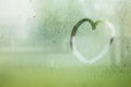 Drawn heart on water drop of rain on window glass burred garden Royalty Free Stock Photo