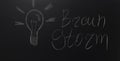 Drawn light on blackboard with the text: Brain Storm.