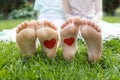 drawn red hearts on the bare feet of two children sitting on the green grass Royalty Free Stock Photo