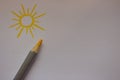 Drawn sun with yellow pencil on white paper background with copy space. Sun picture.