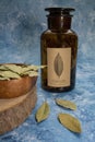 Dray Laurus nobilis Leafs in a wooden plate and dark botanic glass bottle