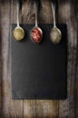 Dray spices on metal spoon on black stone with copy space. Wooden background. Chilli, pepper, marjoram.