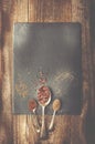 Dray spices on metal spoon on black stone. Wooden background. C