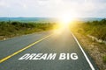 Dream big, concept photo of asphalt road. Motivational inscription on the road going forward. The beginning of a new path. A Royalty Free Stock Photo