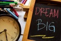 Dream big on phrase colorful handwritten on chalkboard, alarm clock with motivation and education concepts