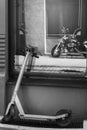 Small e-scooter and big motorcycle in window reflection. Concept of personal growth, life goals or self-acceptance. Royalty Free Stock Photo
