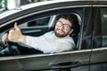 Dream came true. Cheerful man smiling happily showing thumbs up sitting in a big white car Royalty Free Stock Photo