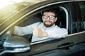 Dream came true. Cheerful man smiling happily showing thumbs up sitting in a big white car Royalty Free Stock Photo