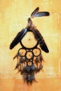 Dream catcher with eagle and raven feathers on orange structure wall