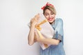 Dream come true! Satisfied young woman in casual blue denim shirt and red headband standing, hugging her present with closed eyes