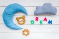 Dream copy for baby pattern with moon pillow, cloud, toy on white wooden background top view
